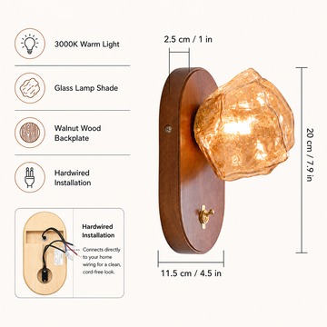 A wall-mounted light fixture with a warm wood backplate and a faceted clear glass shade glowing with a warm amber light, mounted on a beige wall with light rays casting outward.