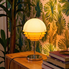 Table lamp on a wooden surface with books and a plant in the background