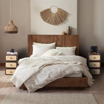 Wooden nightstand with drawers next to a bed in a bedroom setting