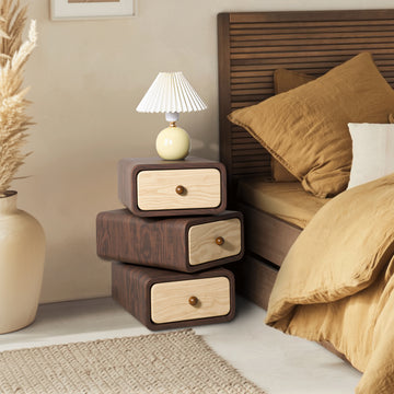 Wooden nightstand with drawers next to a bed in a bedroom setting