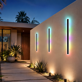 Three vertical black outdoor wall light fixtures with rainbow LED lighting mounted on a beige stucco wall of a modern house at dusk.